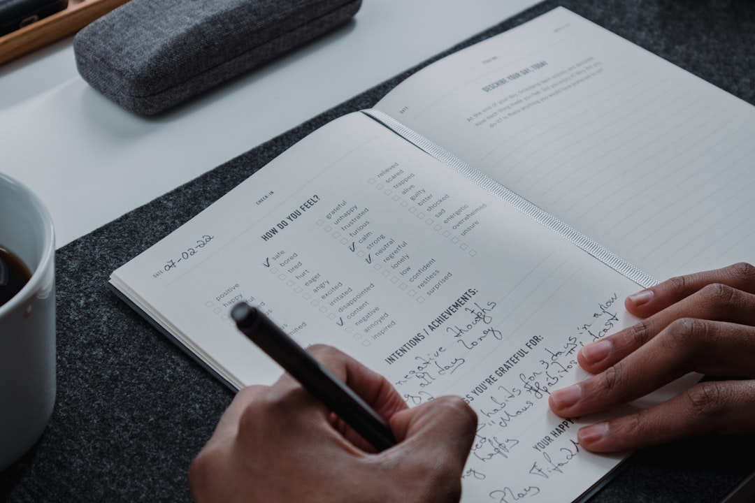 a person writing on a notebook with a pen personal development habits journal wellness