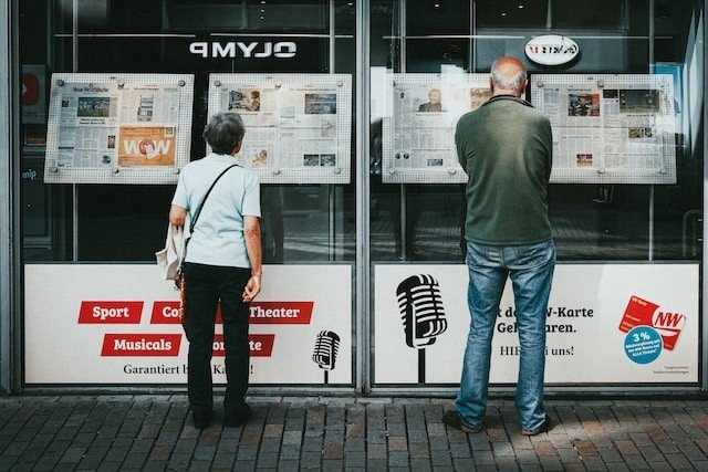 Your headlines need to be attention-grabbing. People looking at newspaper headlines through a window.