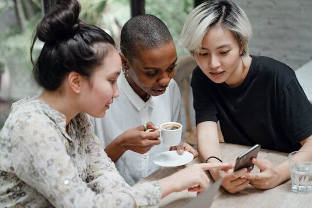 Three friends having coffee and looking at a smartphone.