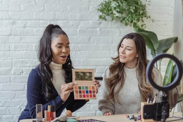 Two women filming a makeup palette, leveraging social media for eCommerce growth.