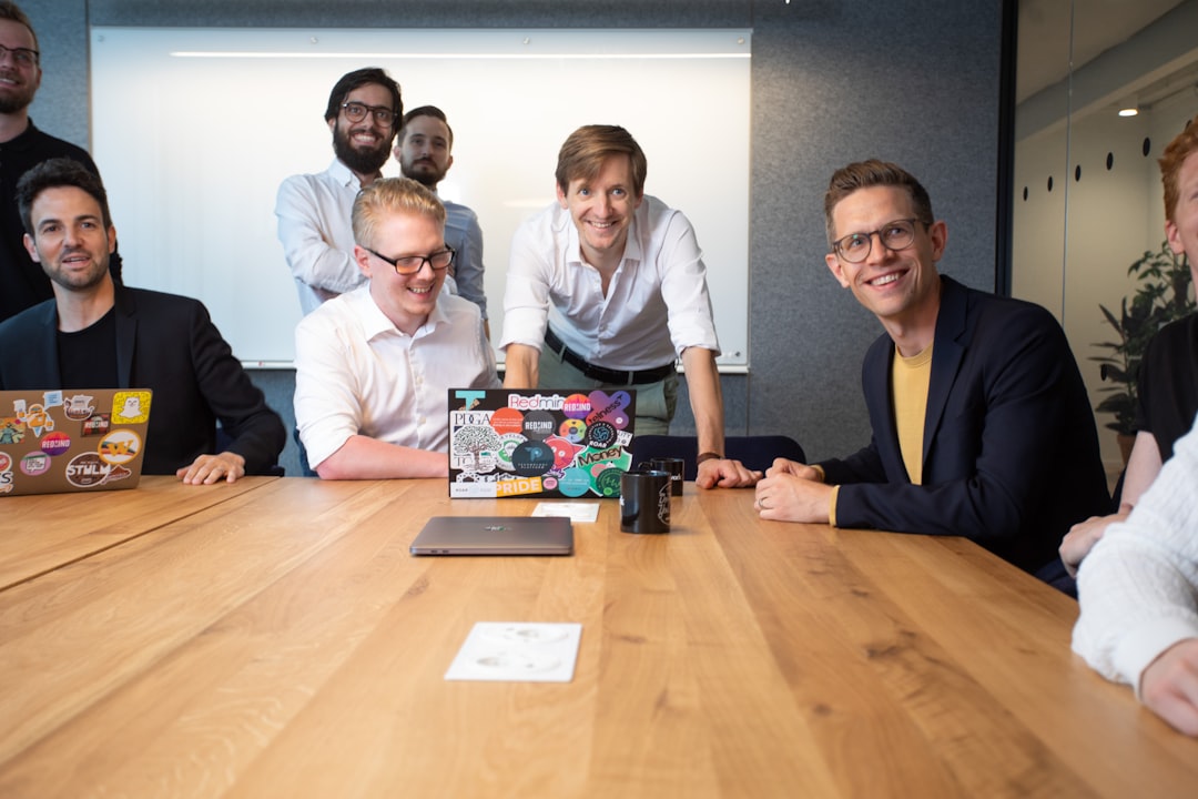 a group of people sitting around a wooden table human robot collaboration content creation happy workspace