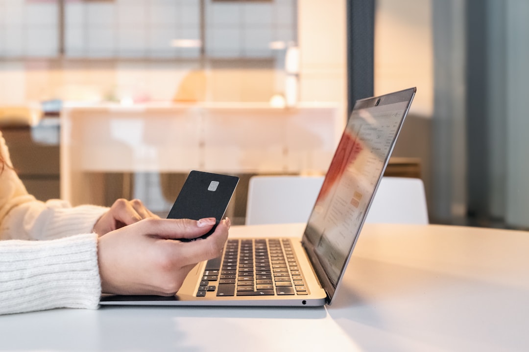 a woman sitting in front of a laptop computer holding a cell phone online payments appointment scheduling