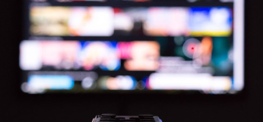 a remote control sitting in front of a television streaming app subscription settings television screen