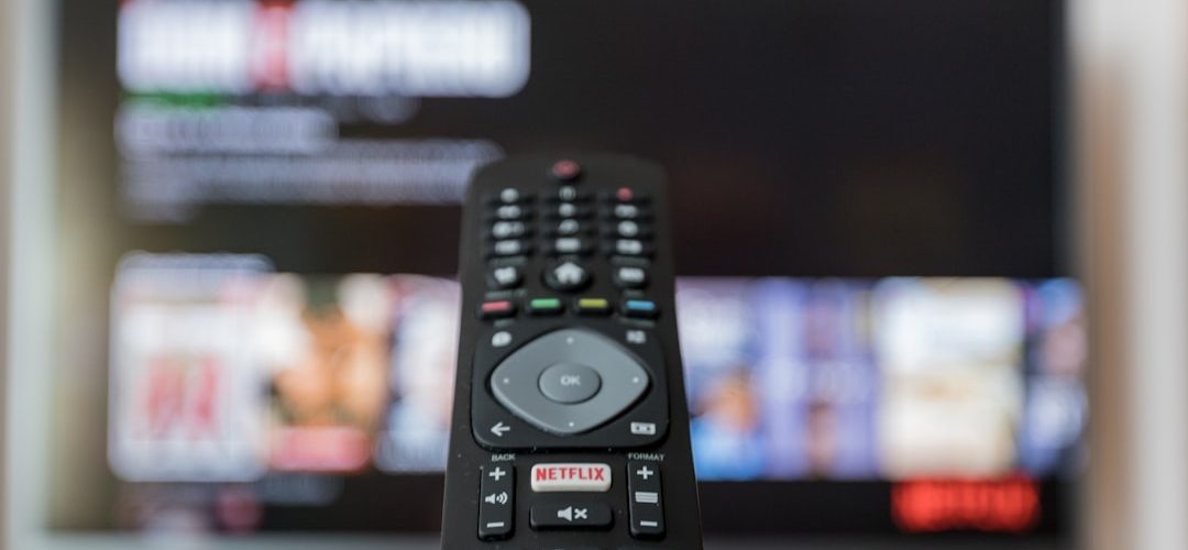 black remote control on brown wooden table streaming app subscription settings television screen