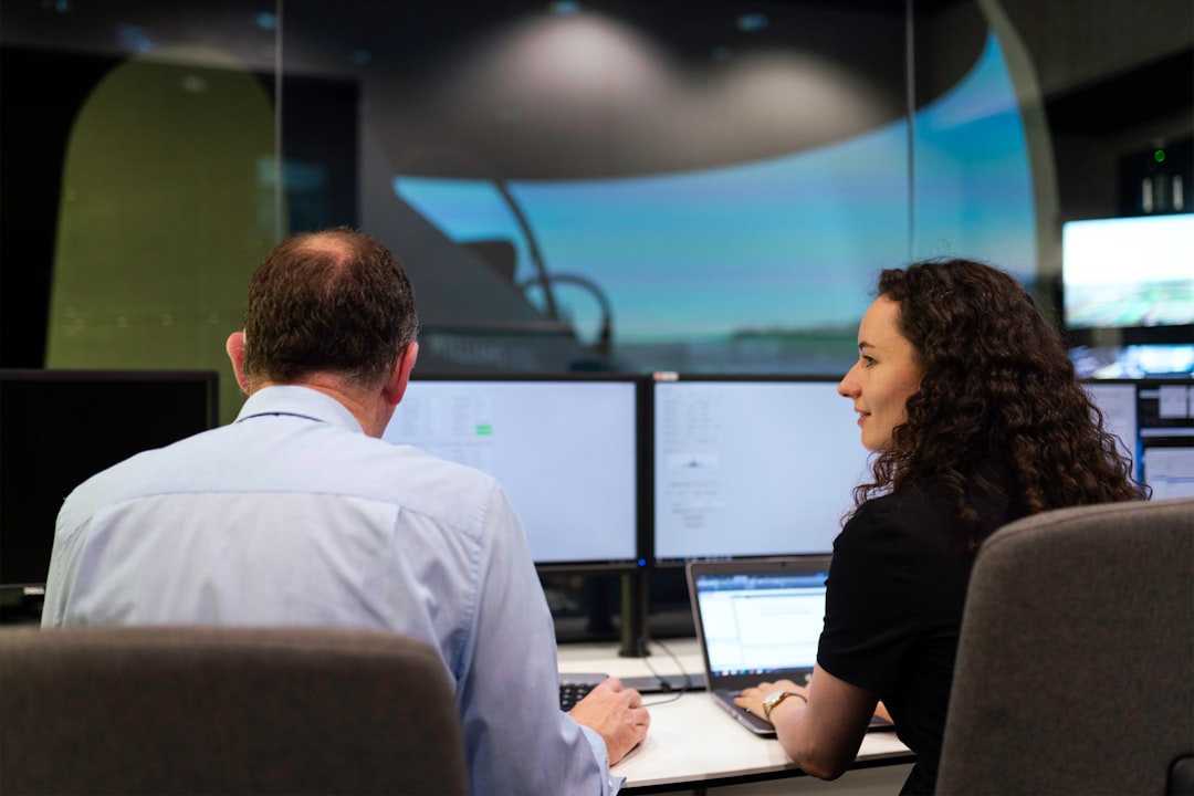 man in white dress shirt sitting beside woman in black shirt technology newsroom digital innovation data screens