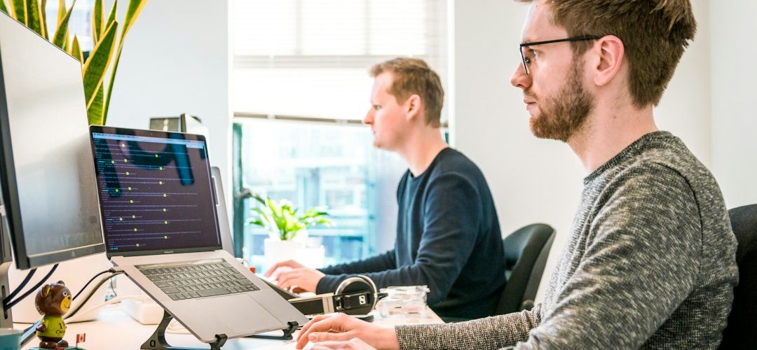 man sitting on chair wearing gray crew neck long sleeved shirt using apple magic keyboard agency team software developers project planning