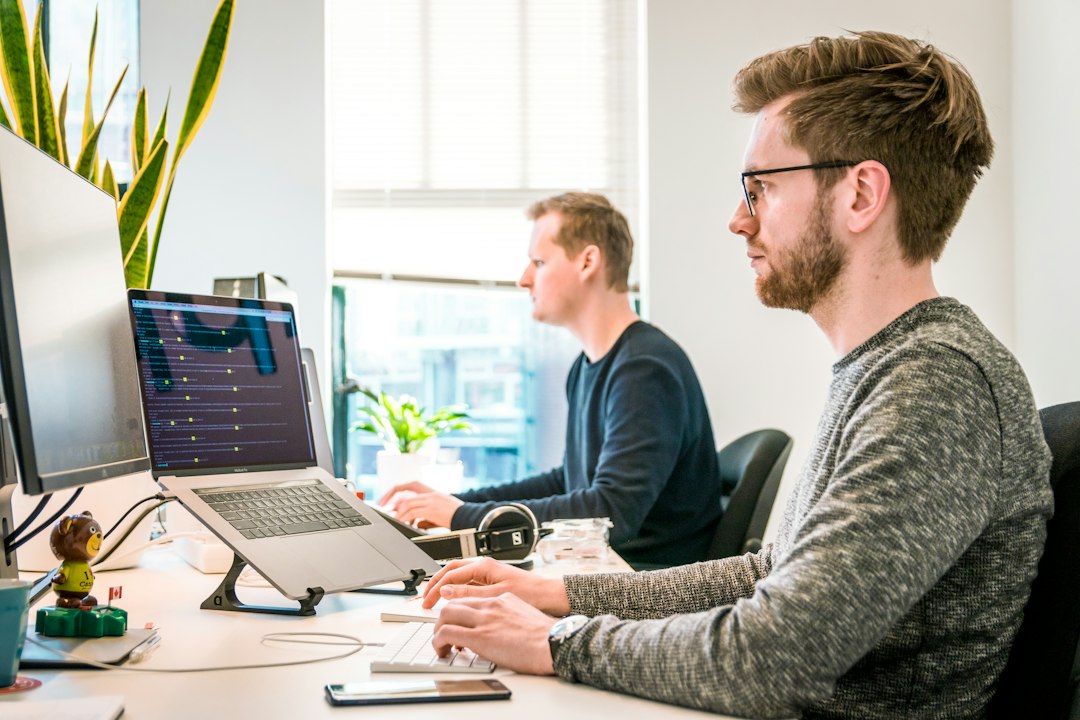 man sitting on chair wearing gray crew neck long sleeved shirt using apple magic keyboard agency team software developers project planning