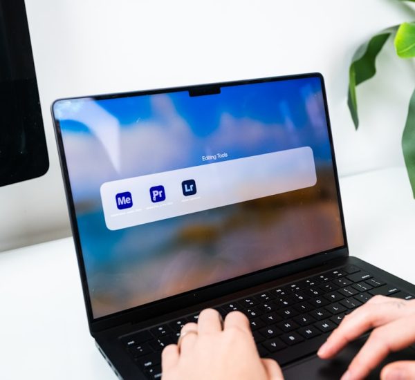 person typing on a laptop with software icons macbook startup screen waveform audio editing creative workspace