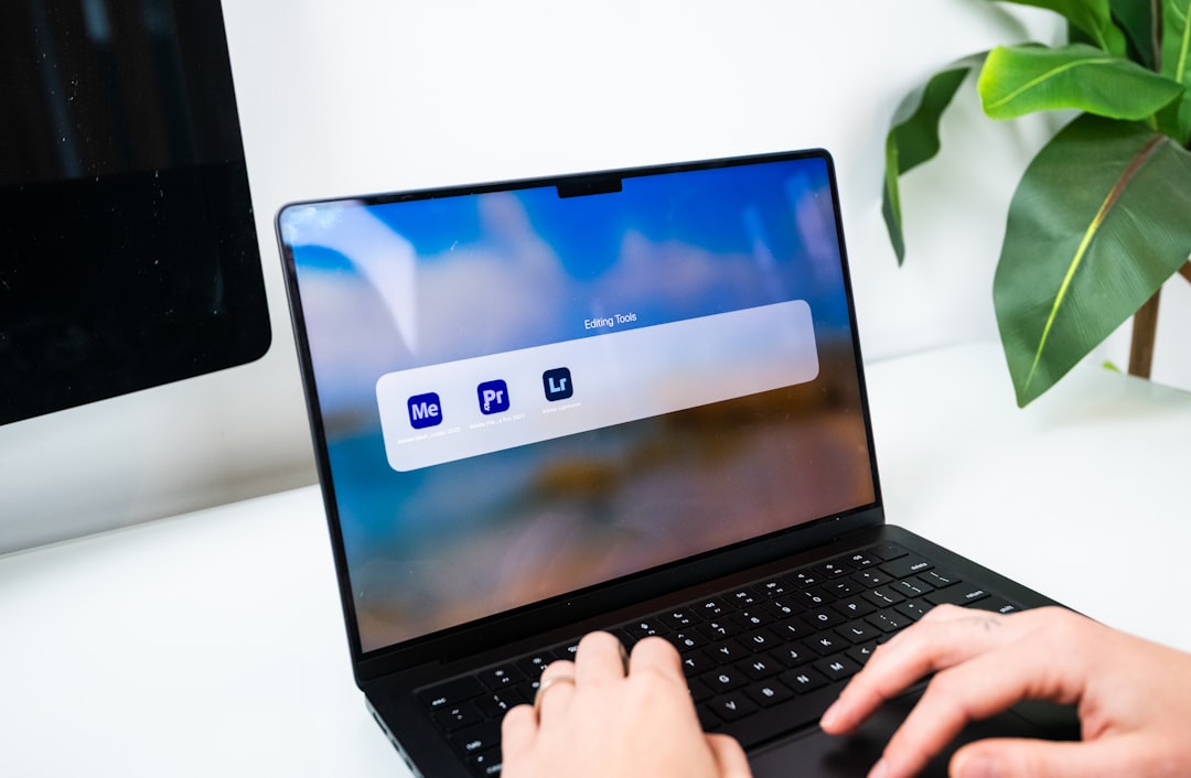 person typing on a laptop with software icons macbook startup screen waveform audio editing creative workspace