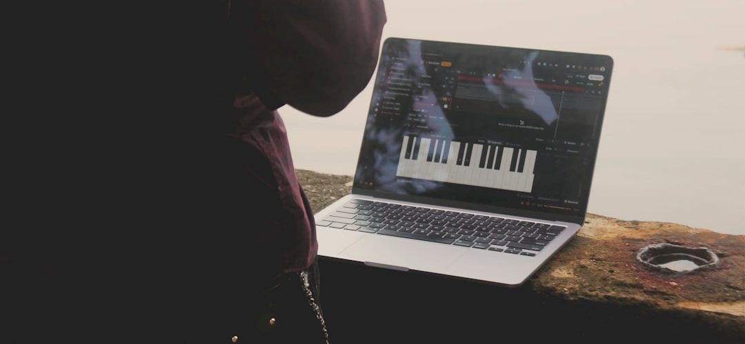 person using laptop with piano interface outdoors macbook startup screen waveform audio editing creative workspace