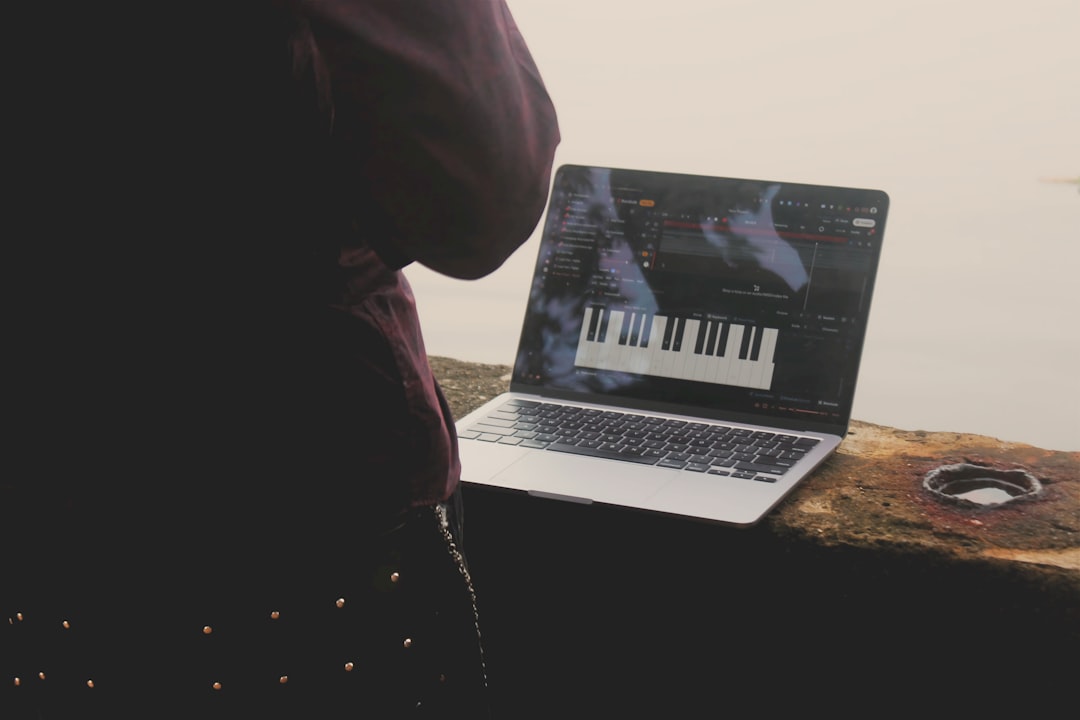 person using laptop with piano interface outdoors macbook startup screen waveform audio editing creative workspace