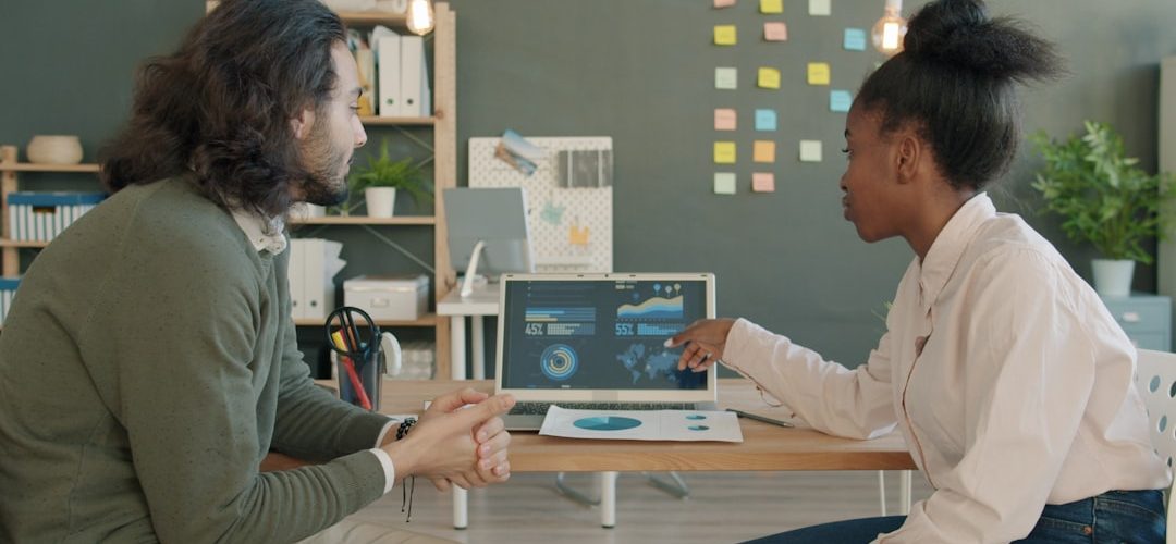 two colleagues discussing data on a laptop screen connected data digital transformation business growth analytics team