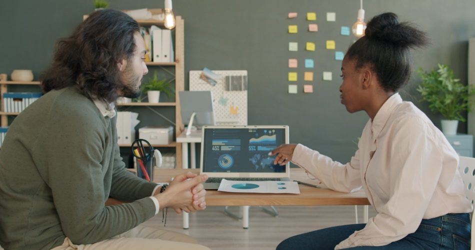 two colleagues discussing data on a laptop screen connected data digital transformation business growth analytics team