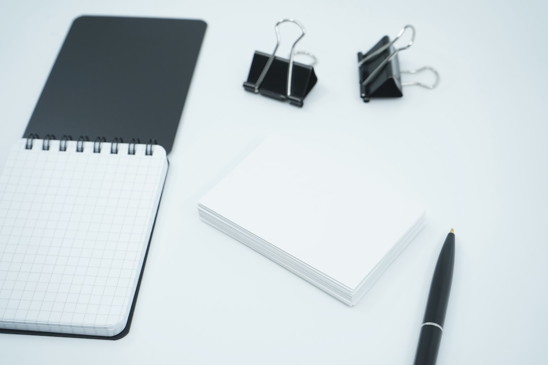 white and black notebook beside black pen business cards color swatches office desk 1