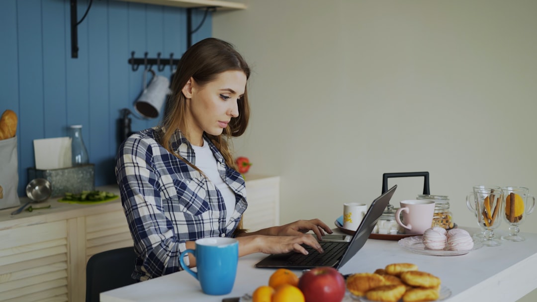 woman working on laptop in a bright kitchen ai tools freelancer workspace online income