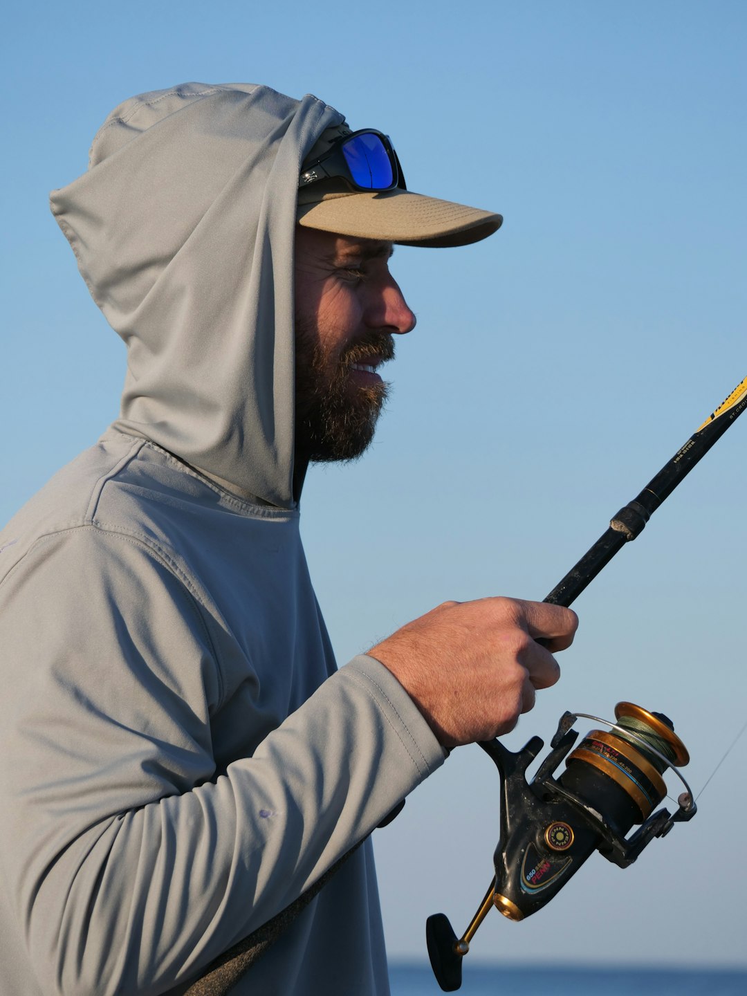 a man in a hoodie holding a fishing rod fishing apparel hats logo patch tackle