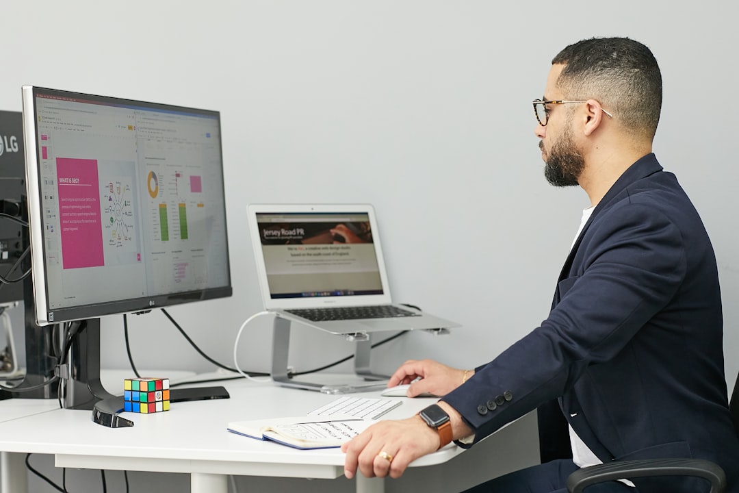 a man sitting at a desk with a laptop and a computer business software dashboard client management team workflow 1