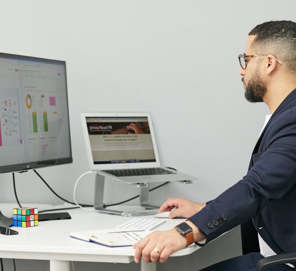 a man sitting at a desk with a laptop and a computer business software dashboard client management team workflow
