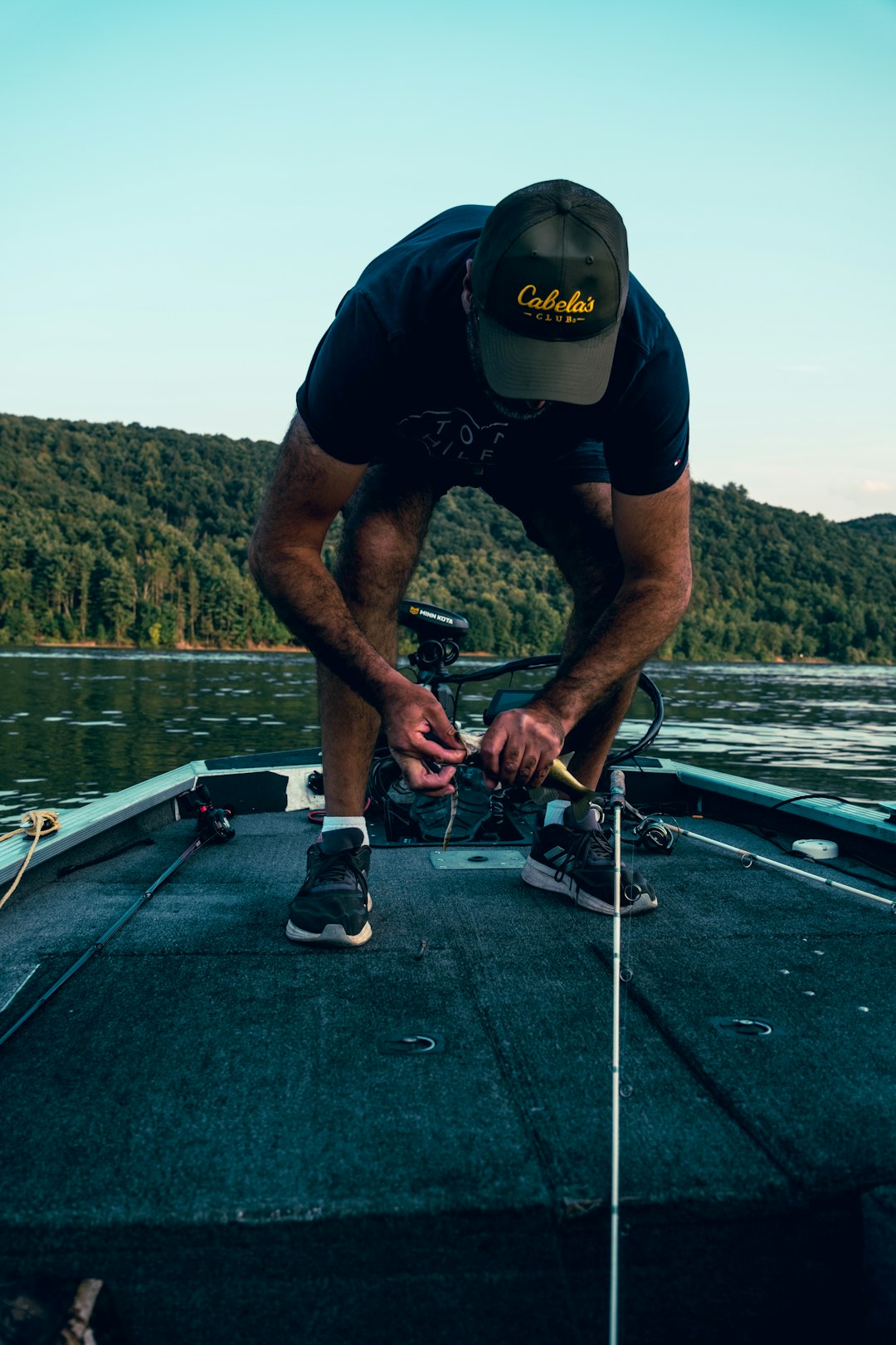 a man tying a fishing line on a boat fishing apparel hats logo patch tackle