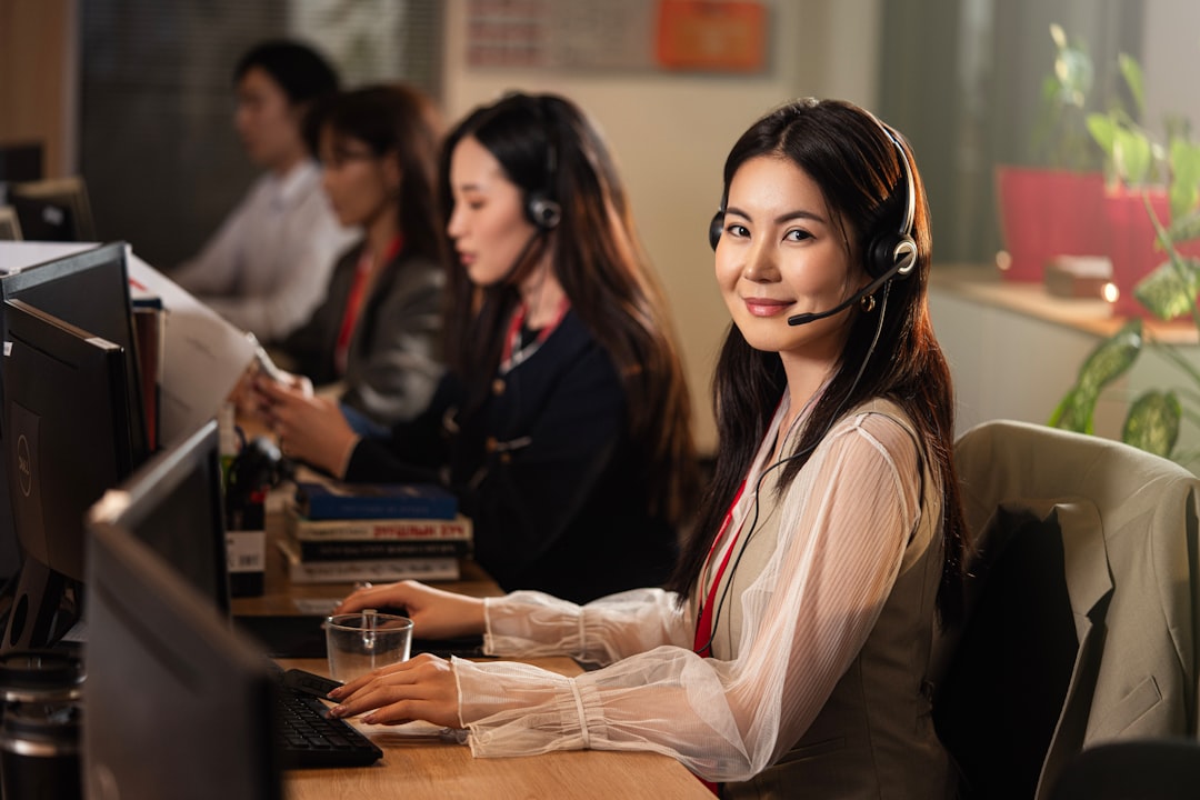 a smiling woman wearing a headset at a computer operations center dashboard cloud metrics team