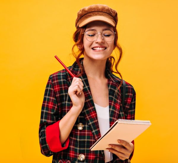 How to Create a Successful List Blog 8 a woman in a plaid jacket holding a pen and notebook study notes quiz checklist smiling student