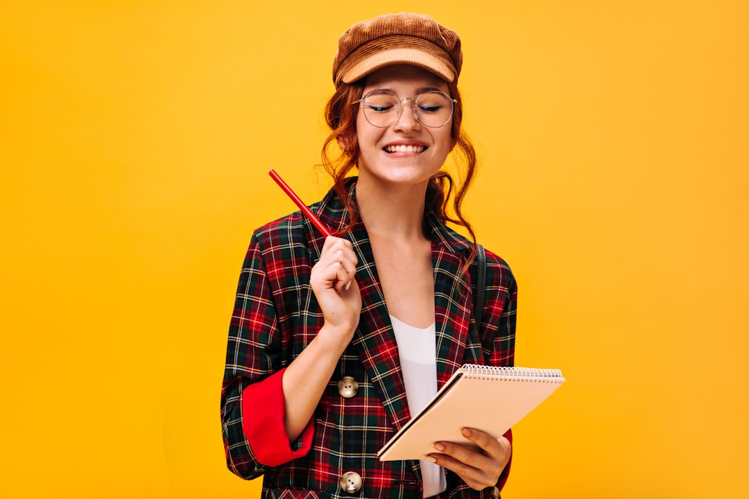 a woman in a plaid jacket holding a pen and notebook study notes quiz checklist smiling student