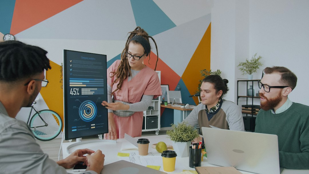 a woman presenting data on a monitor to three colleagues in a workspace presentation markup colored arrows team feedback