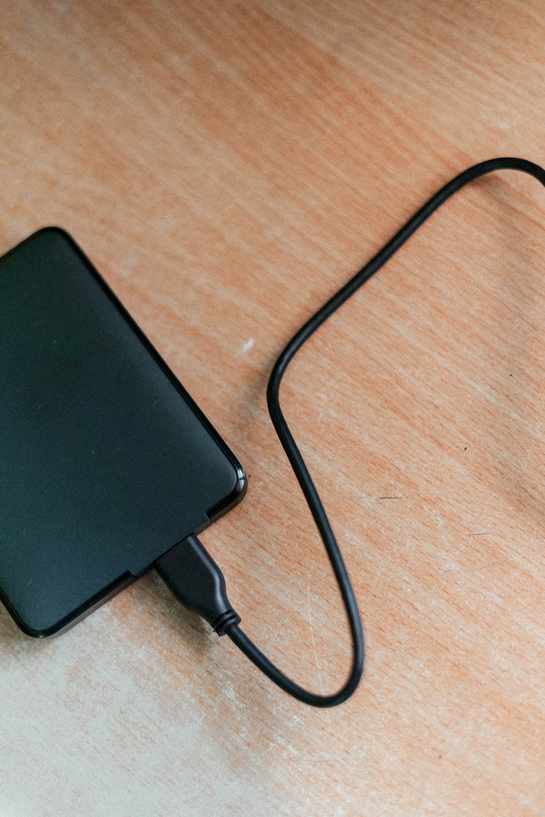 black power bank on brown wooden table power bank phone charging usb cable travel gear