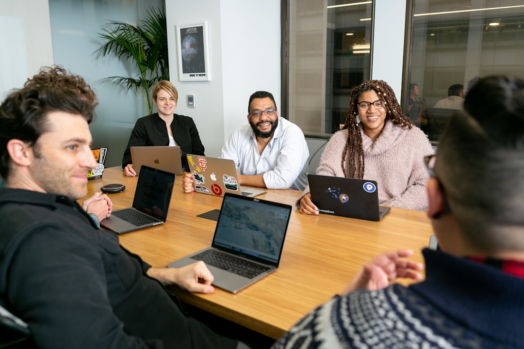 four people all on laptops two men and two women listen to person talking in a board meeting team reviewing funnel optimization meeting data insights