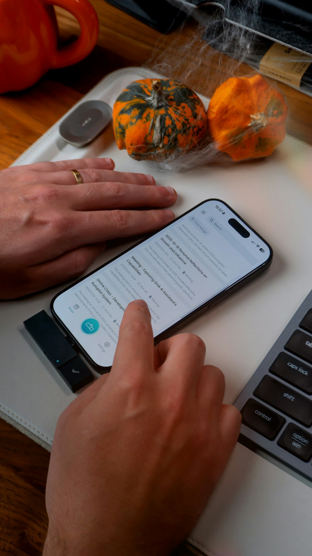hands using a smartphone next to pumpkins and keyboard person using ai clear prompts digital assistant