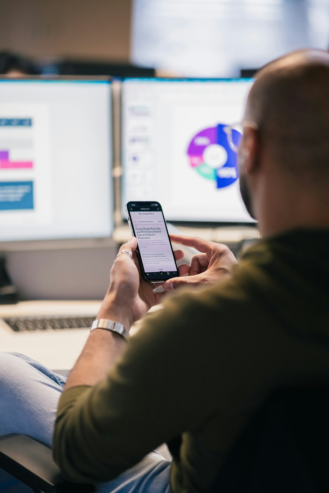 man using smartphone in front of computer monitors enterprise mobile dashboard data visualization secure access professional users