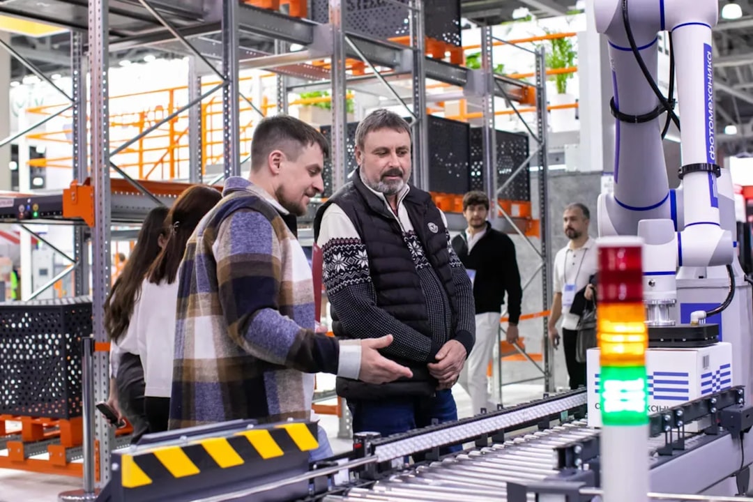 men observe automated conveyor belt system in warehouse industrial 3d printing engineered parts manufacturing facility