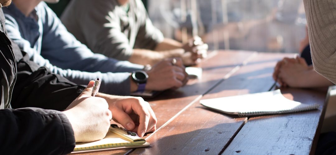 people sitting on chair in front of table while holding pens during daytime business meeting strategy board team alignment objectives