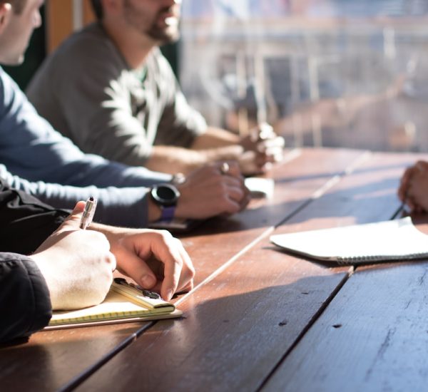 What Is a QBR? Quarterly Business Review Guide With Templates 9 people sitting on chair in front of table while holding pens during daytime business meeting strategy board team alignment objectives