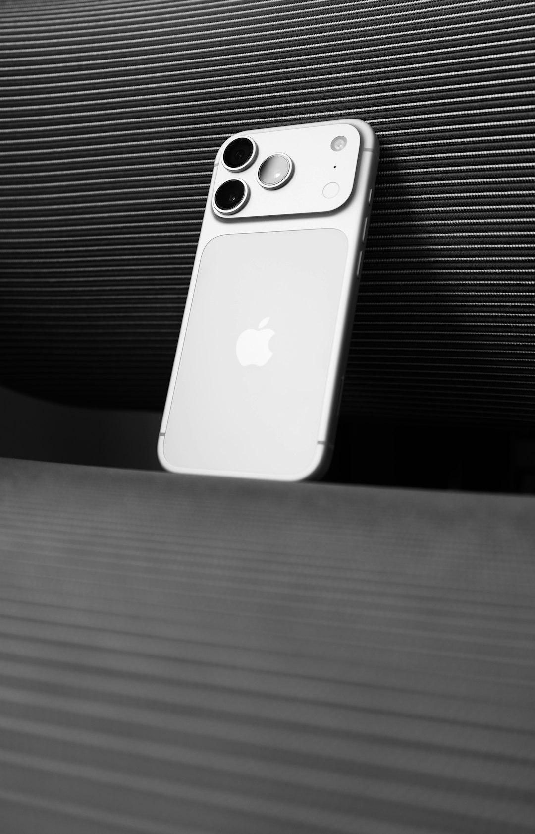 silver smartphone with apple logo against striped background apple flagship phones blue pro max smartphone lineup studio lighting