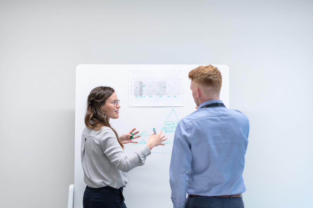 two colleagues discussing ideas at whiteboard business meeting strategy board team alignment objectives
