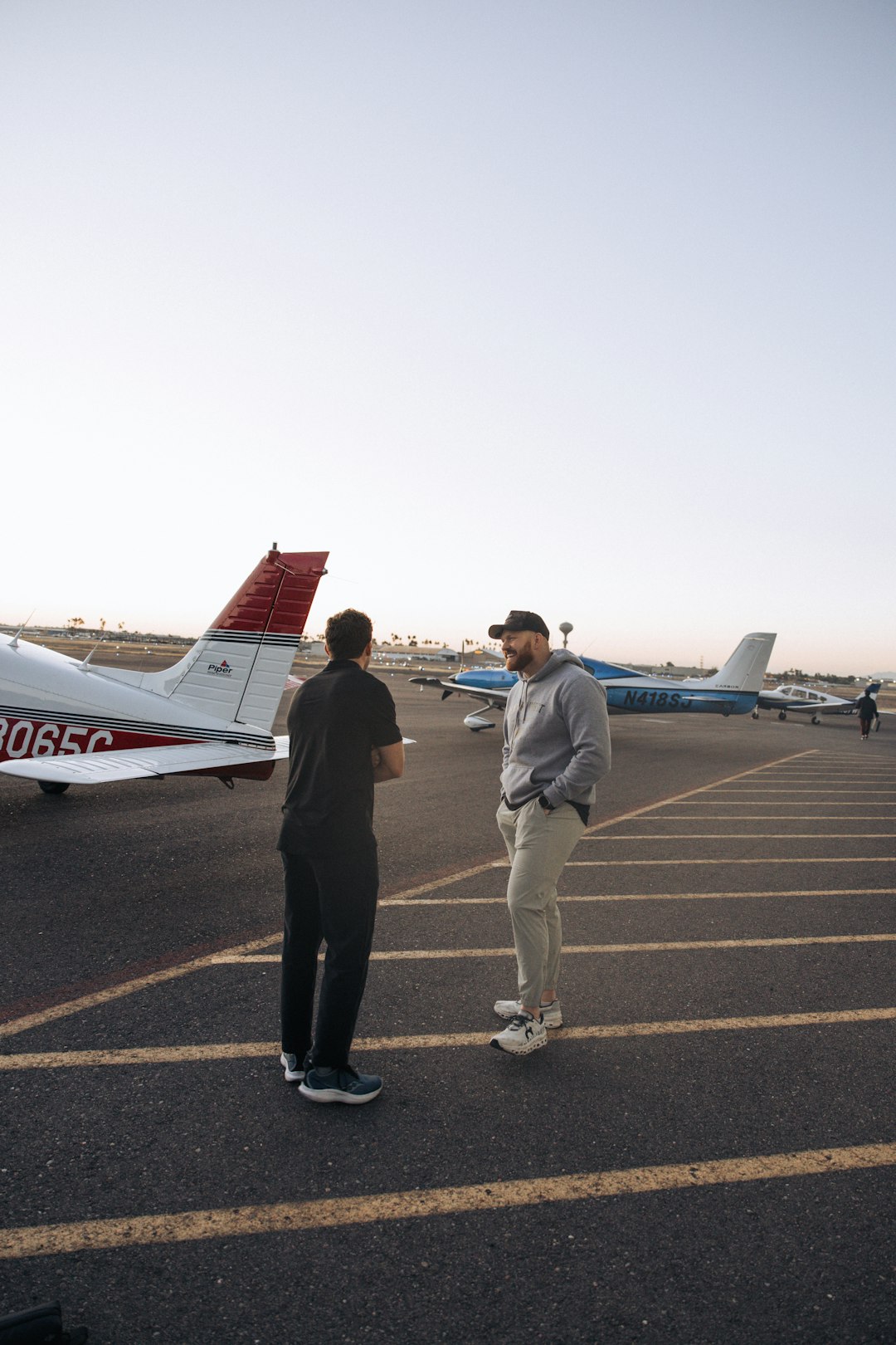 two men talking on an airfield with small planes flight instructor student pilot ground lesson airplane model