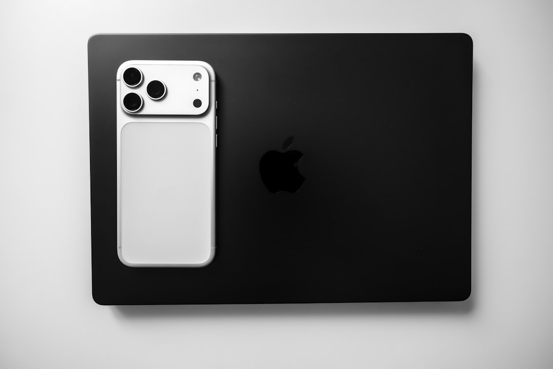 white smartphone resting on black laptop macbook iphone ipad productivity app apple ecosystem