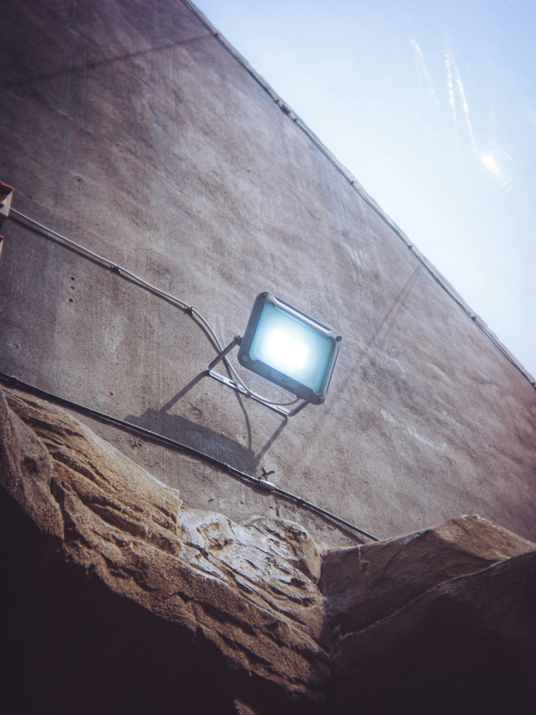 a bright floodlight illuminates a rough concrete wall infrared floodlight security camera outdoor wall