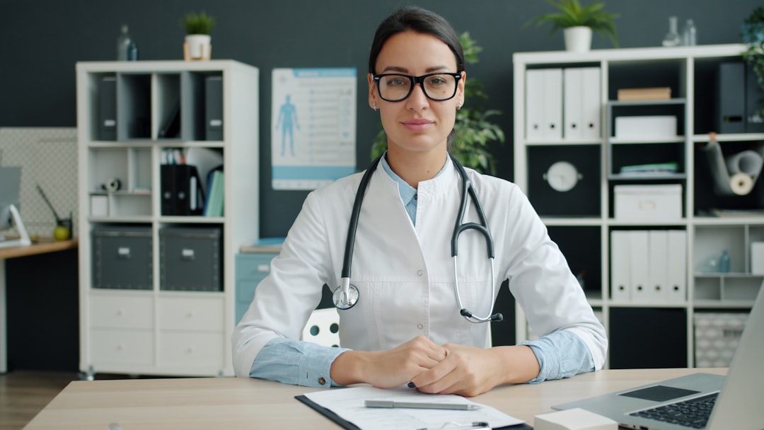 a female doctor wearing a stethoscope sits at her desk doctor office patient payments billing software