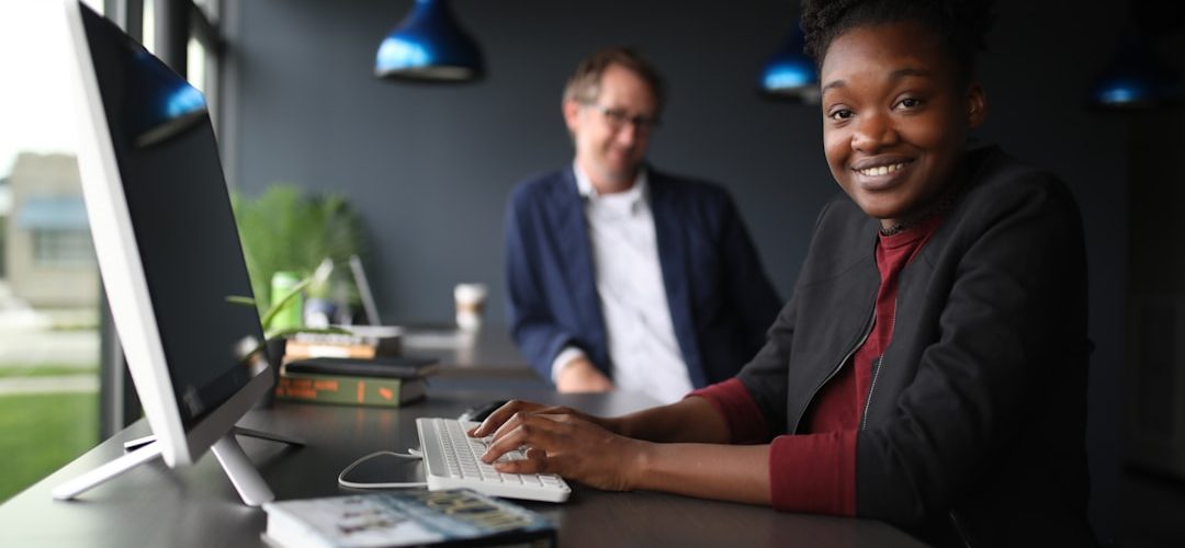 a man and a woman sitting at a desk in front of a computer customer support team dashboard smiling