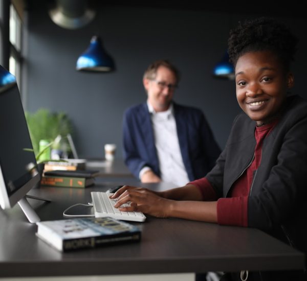 9 Help Desk Outsourcing Companies for 24/7 Customer and IT Support 2 a man and a woman sitting at a desk in front of a computer customer support team dashboard smiling
