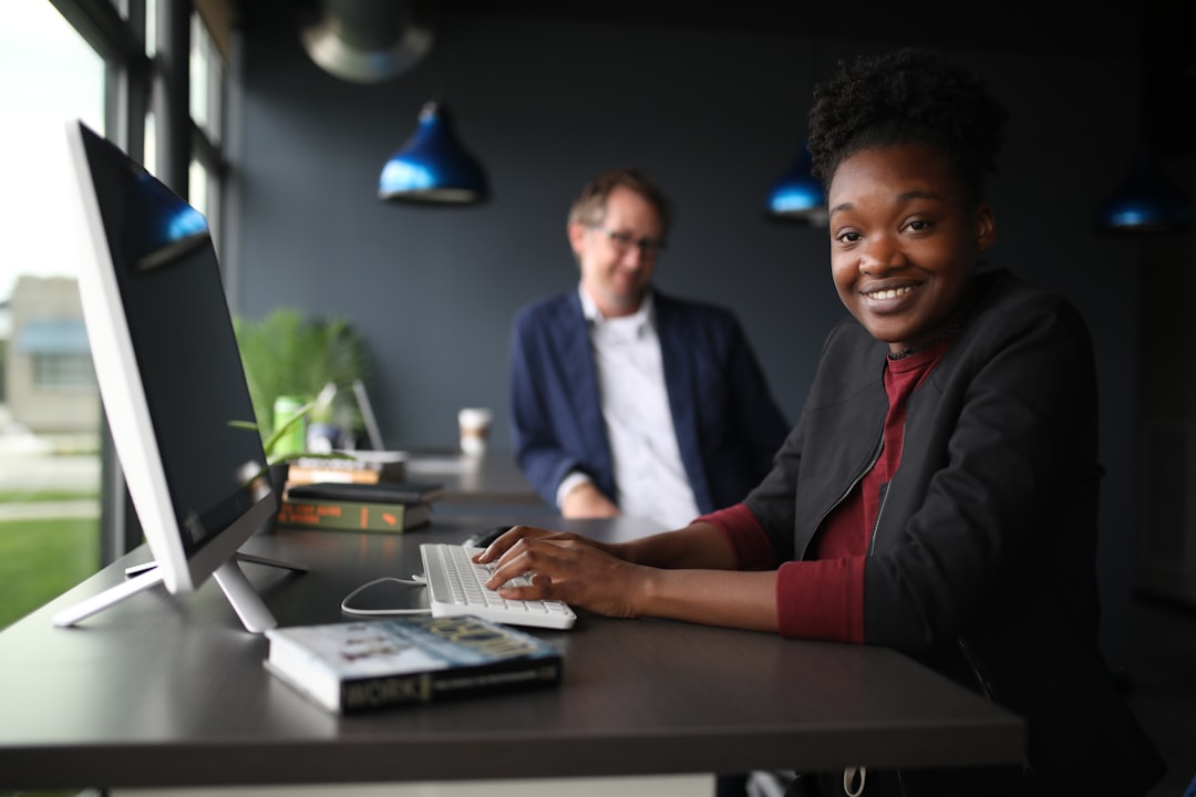 a man and a woman sitting at a desk in front of a computer customer support team dashboard smiling
