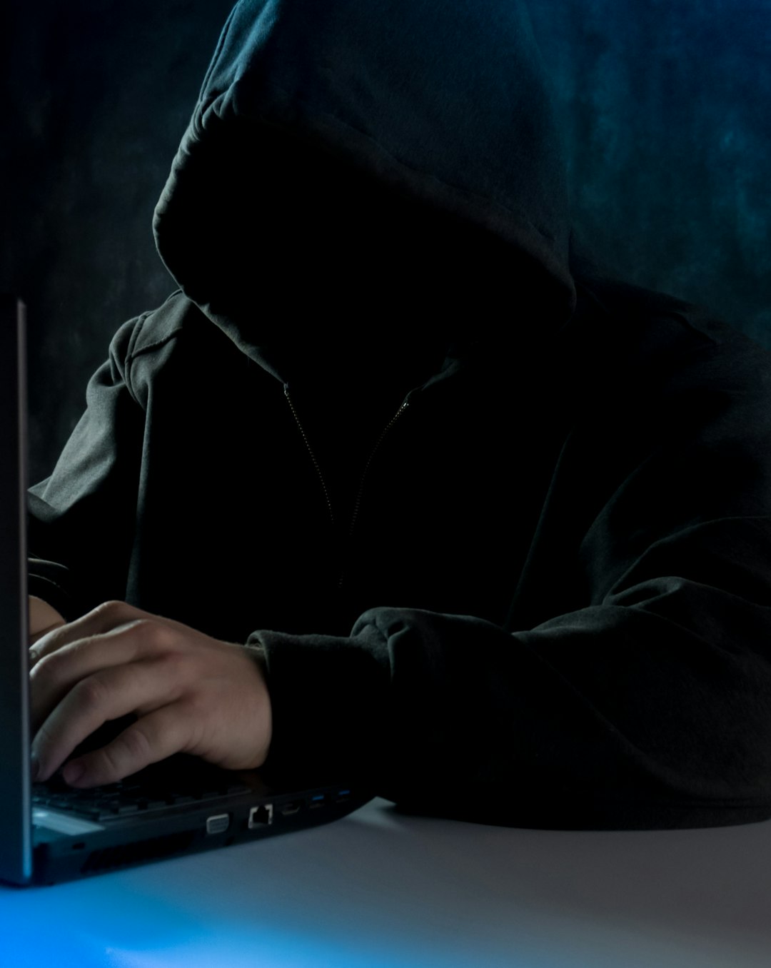 a man in a hoodie using a laptop computer cybersecurity investigation data breach forensic evidence