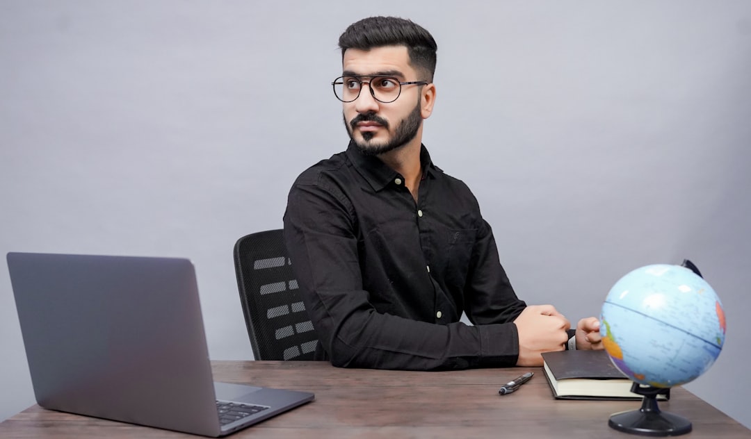 a man sitting at a desk with a globe and a laptop global employees online training multilingual learning
