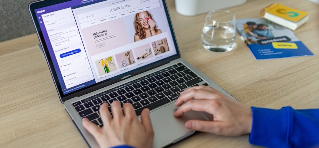 a person typing on a laptop on a table ecommerce website laptop shopping cart