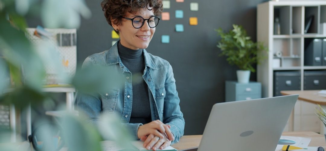 a smiling woman with curly hair works at a laptop shared folders remote workers digital documents