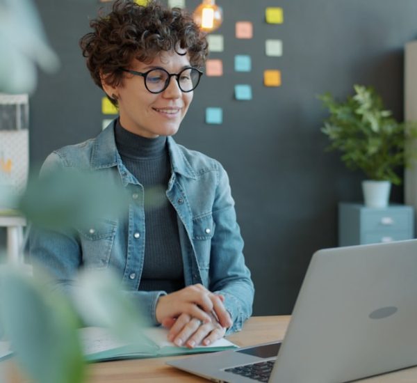 Inside Sales vs Outside Sales: Key Differences, Benefits, and Career Paths 8 a smiling woman with curly hair works at a laptop shared folders remote workers digital documents