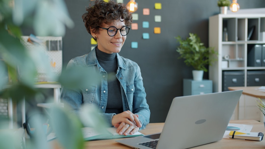 a smiling woman with curly hair works at a laptop shared folders remote workers digital documents