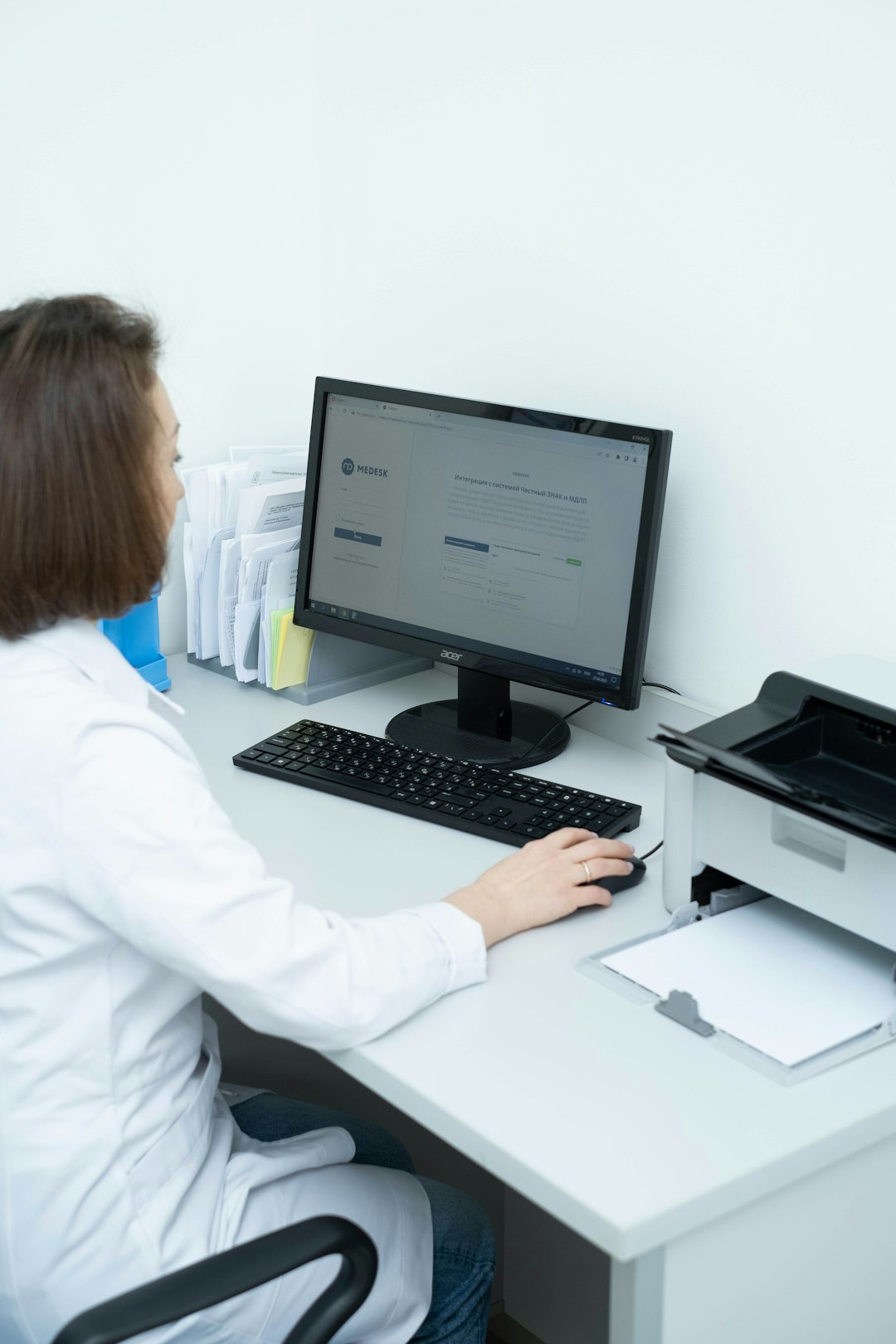 a woman sitting at a desk using a computer insurance claims medical coding automated workflow